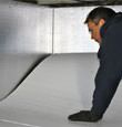 A contractor installing TerraBlock™ floor insulation in a Salida crawl space